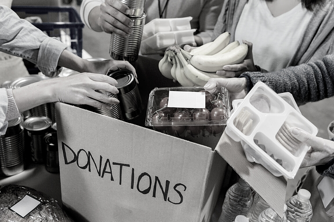 Unrecognizable food bank volunteers unpack donation box